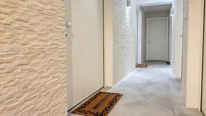 A hallway with textured walls, a doormat, and a door at the end. - N&J - LE SALEYA - Old Town - Very close sea (Niza)