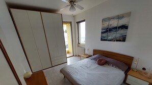 Ein Schlafzimmer mit Bett, Nachttischen, einem Kleiderschrank und einem Deckenventilator.