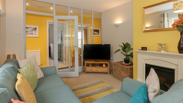 Un salon avec un canapé, une télévision, une cheminée et un miroir au mur.