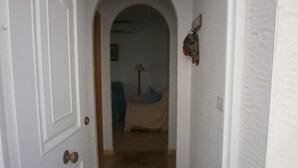 Ein Flur, der in ein Schlafzimmer mit Bett, Lampe und Wanddekoration führt.