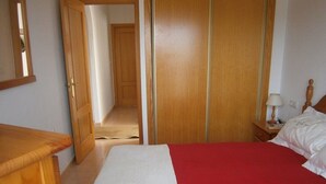 Ein Schlafzimmer mit einem Bett, einem Holzschrank und einem Nachttisch mit Lampe.