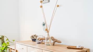 A wooden dresser with a glass vase containing dried flowers and a peacock feather.