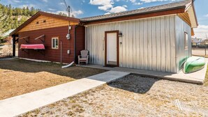 A two-story building with a red exterior and a white garage door. - Paddlers Inn - Canoe Shop | Rustic | Quaint | Cozy (Canal Flats)
