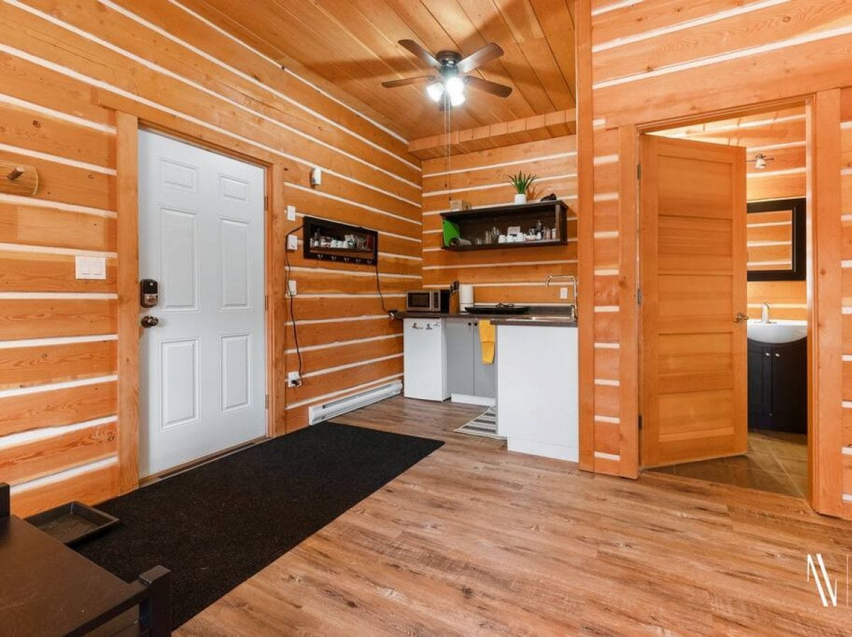 A log cabin interior with a kitchen, a bathroom, and a dining area.