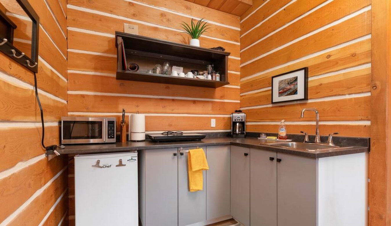 A compact kitchen with wooden paneling, a microwave, a coffee maker, and a sink.