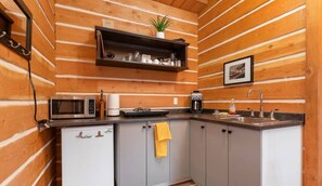 A compact kitchen with wooden paneling, a microwave, a coffee maker, and a sink. - Paddlers Inn - Canoe Shop | Rustic | Quaint | Cozy (Canal Flats)