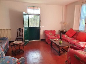 A living room with a green door, floral sofas, a wooden coffee table, and a radiator.
