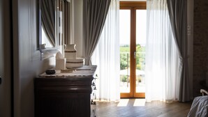 Una habitación con un aparador de madera, un espejo y una puerta que da a un balcón con cortinas.