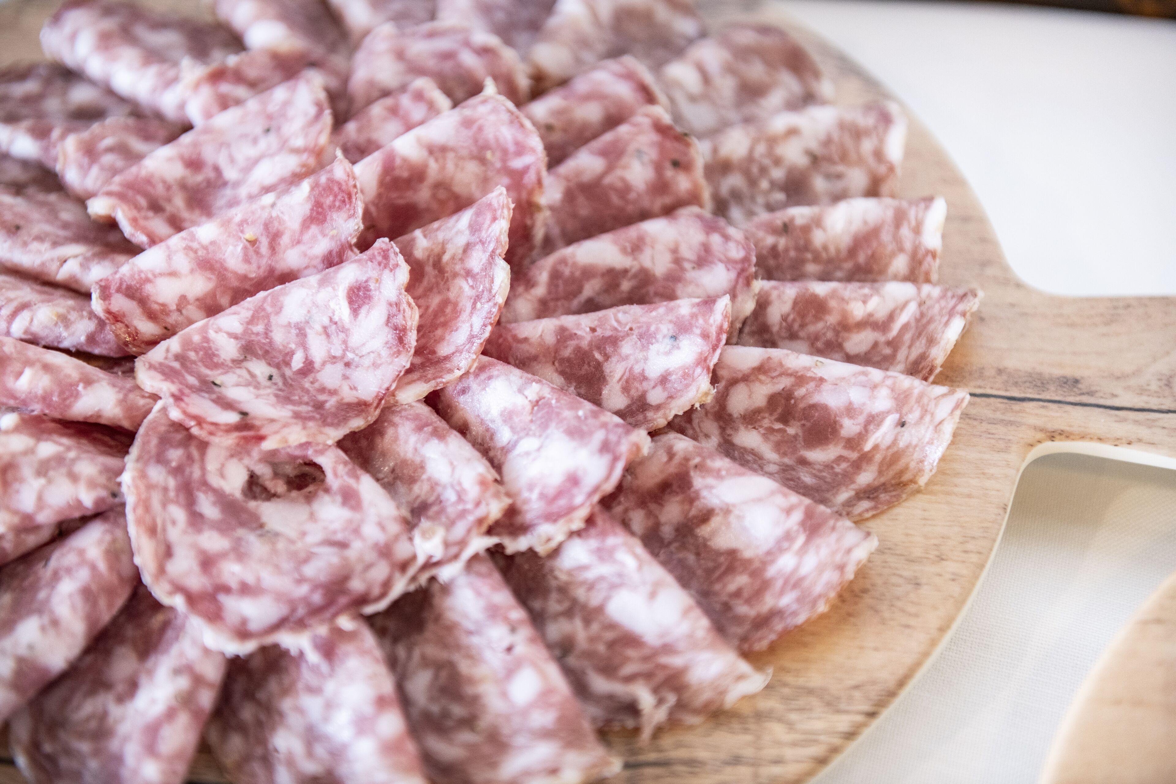 Une planche à découper en bois sur laquelle des tranches de salami sont disposées en cercle.