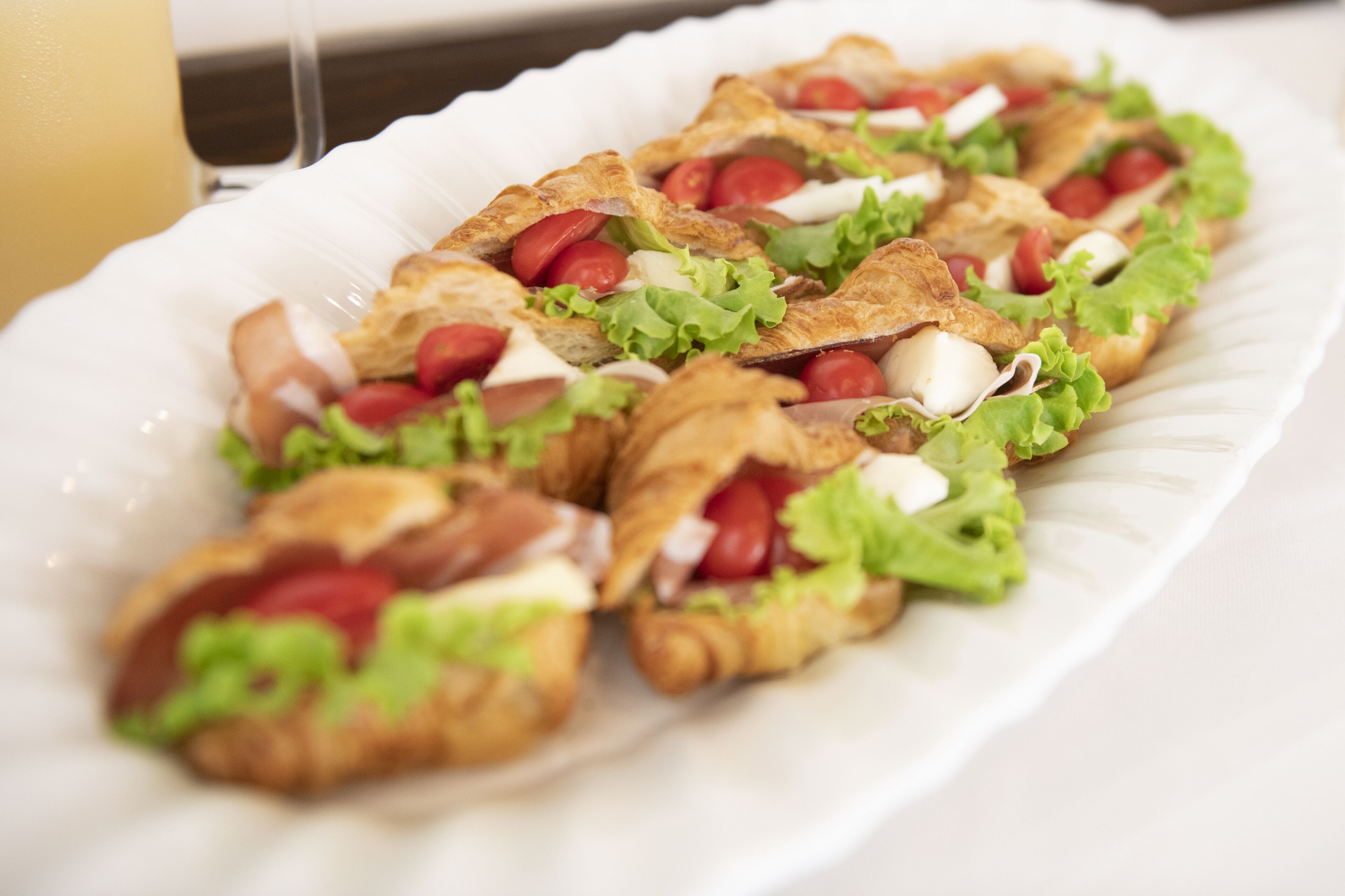 A plate of crostini with tomatoes, lettuce, and cheese.