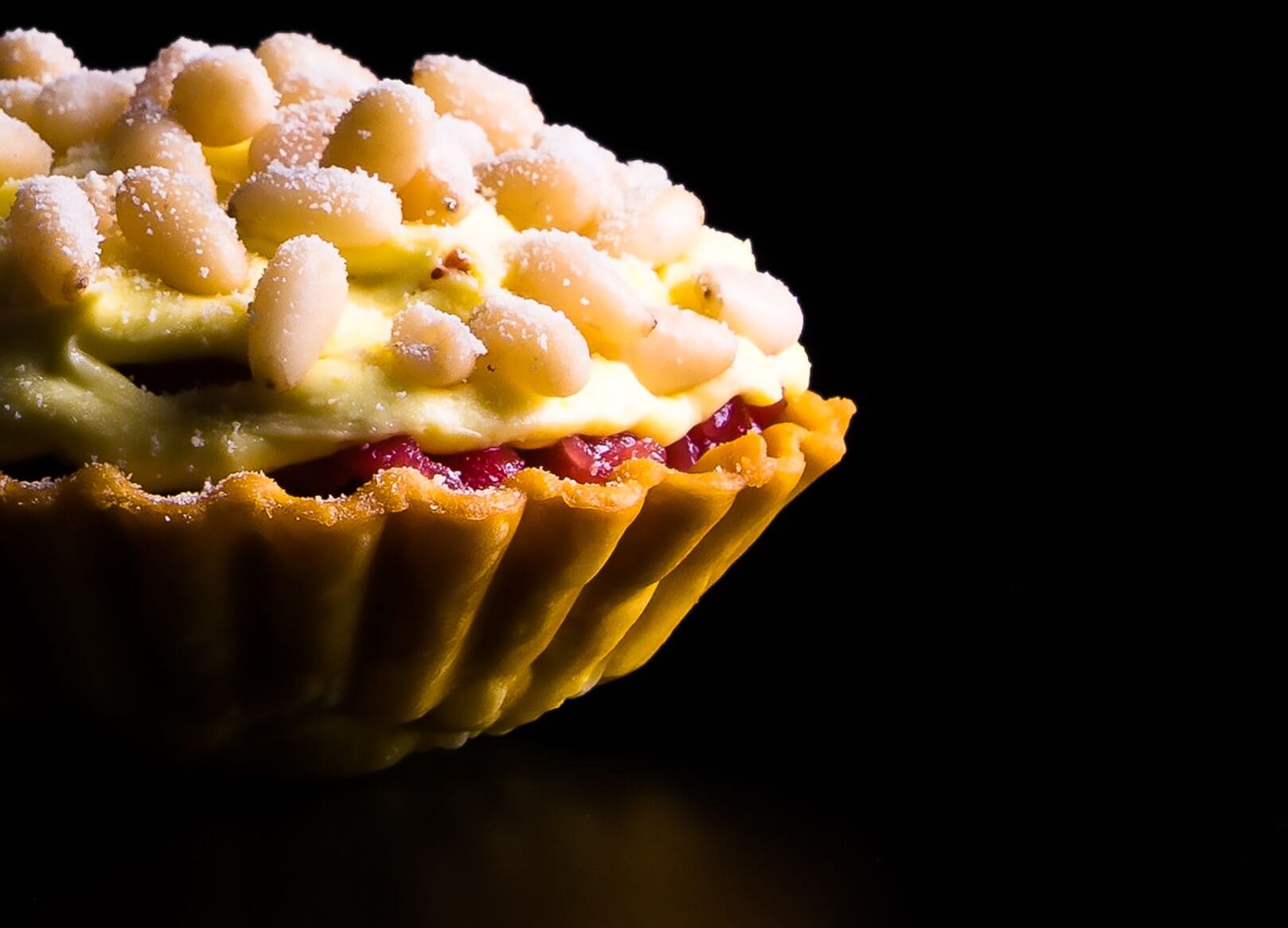 Ein Detailaufnahme eines Tartes mit goldbrauner Kruste und cremiger Füllung, verziert mit Zuckerperlen.