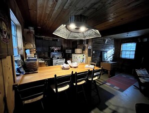 Cozy cabin-style dining area with a wooden table and pendant light, surrounded by comfortable chairs.