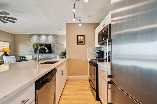Une cuisine moderne dotée d’appareils électroménagers en acier inoxydable, d’un plan de travail en granit et d’un plancher en bois.
