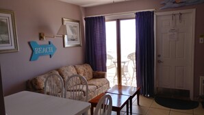 Una sala de estar con un sofá, una mesa y sillas. Hay un letrero en la pared que dice "BEACH".
