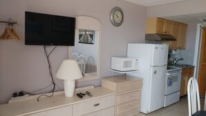 Una kitchenette compacta con microondas, refrigerador y un reloj de pared.