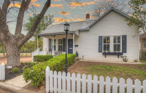 A single-story house with a porch, white picket fence, and a well-maintained lawn.