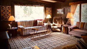 Un salon chaleureux avec un tapis à motifs, un fauteuil à bascule, un canapé et deux lampes.