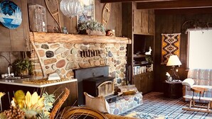Un intérieur rustique avec une cheminée en pierre, des meubles en bois et un tapis à motifs.
