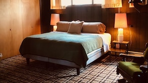 Une chambre confortable avec un grand lit, deux lampes de chevet, une fenêtre avec des rideaux et un tapis à motifs.