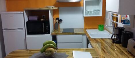 A compact kitchen with a refrigerator, microwave, and a sink.