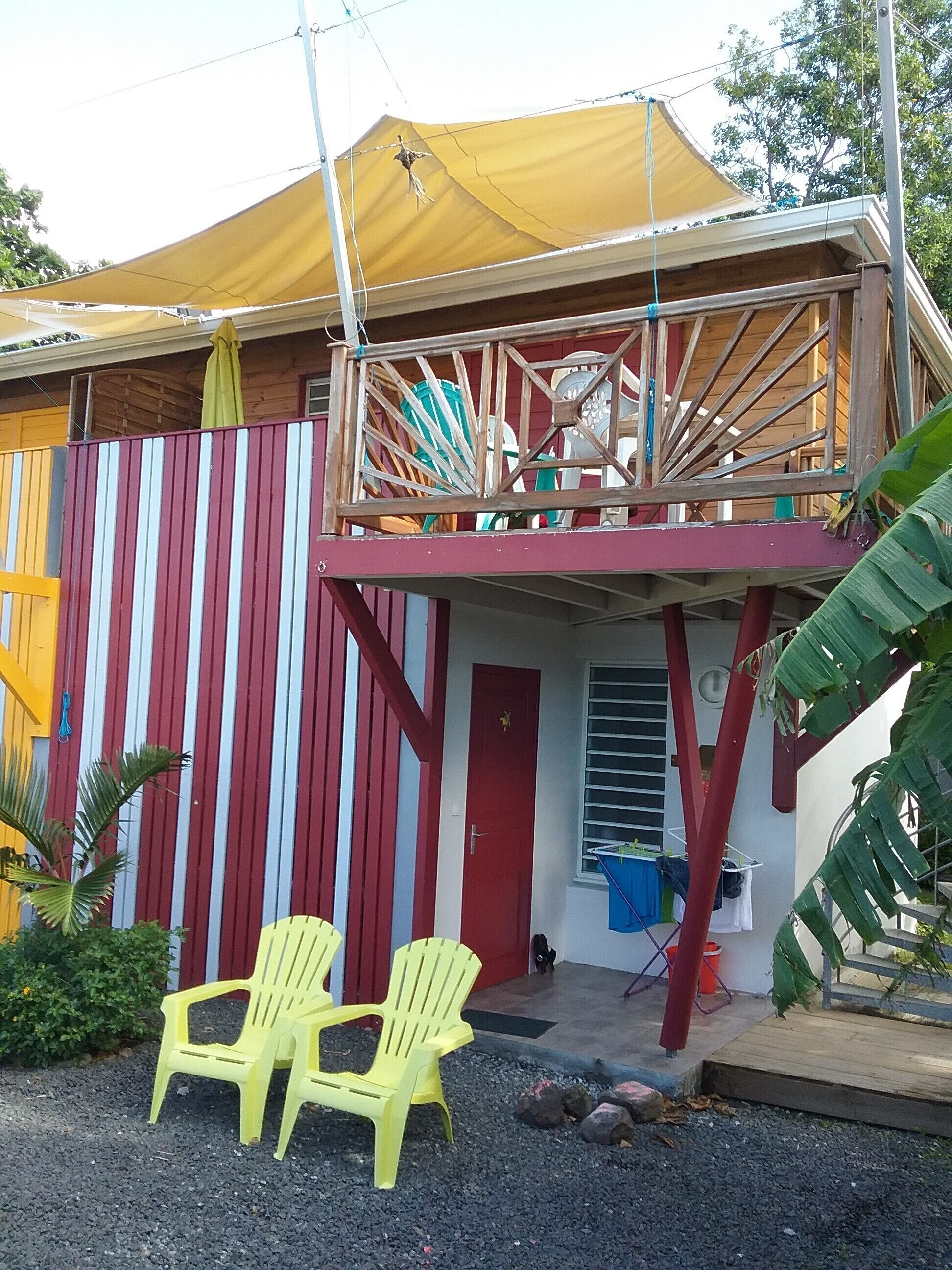 A two-story building with a balcony, a red door, and a yellow awning.