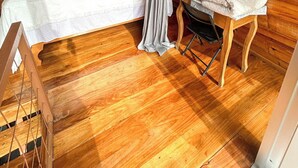 Une chambre confortable dans un chalet en bois, avec un lit, une petite table et une lampe, ainsi qu’une fenêtre avec un rideau.