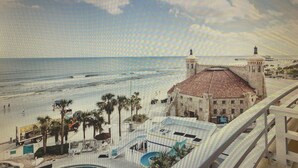 Ein Hotel mit Pool, Palmen und Blick auf Strand und Meer.