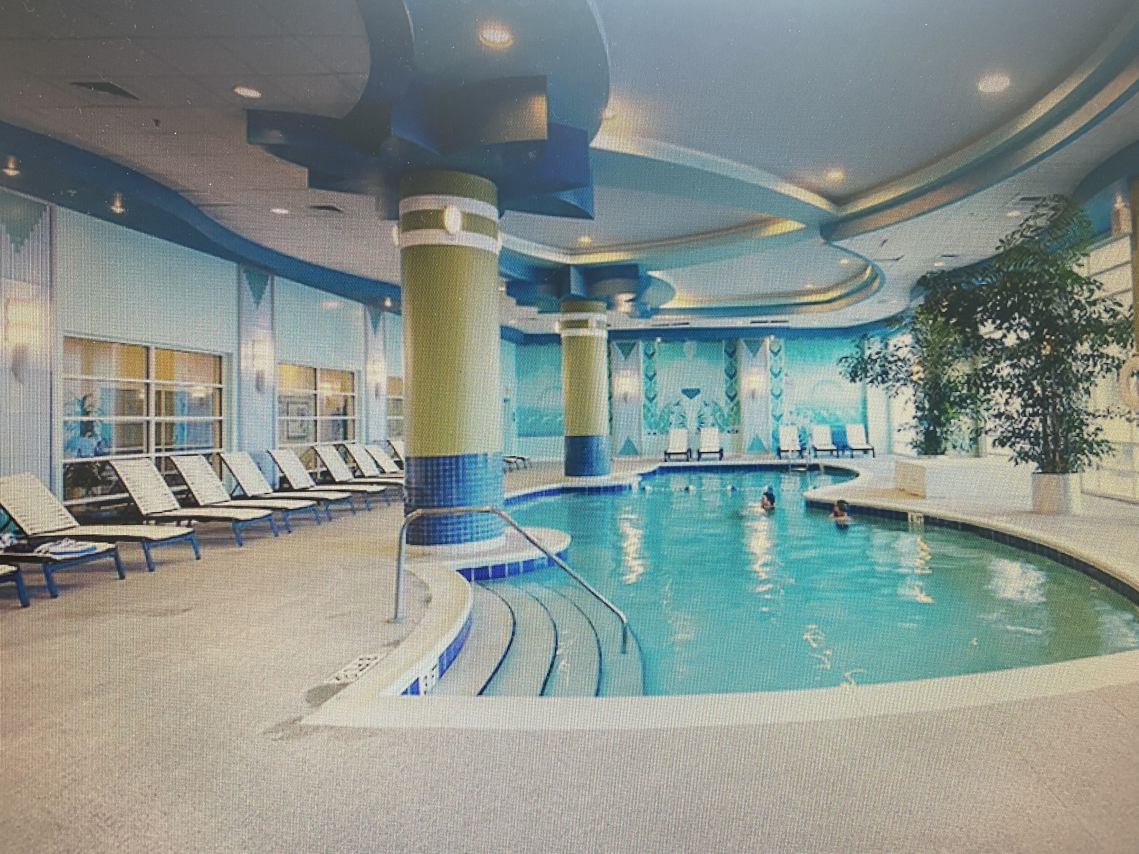 An indoor swimming pool with lounge chairs and a large pillar.
