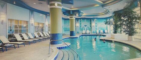 An indoor swimming pool with lounge chairs and a large pillar.