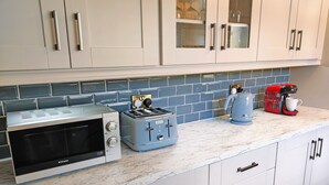 A kitchen with white cabinets, a microwave, a toaster, and a coffee maker on a marble countertop. - Tralee Townhouse Holiday Home (Tralee)