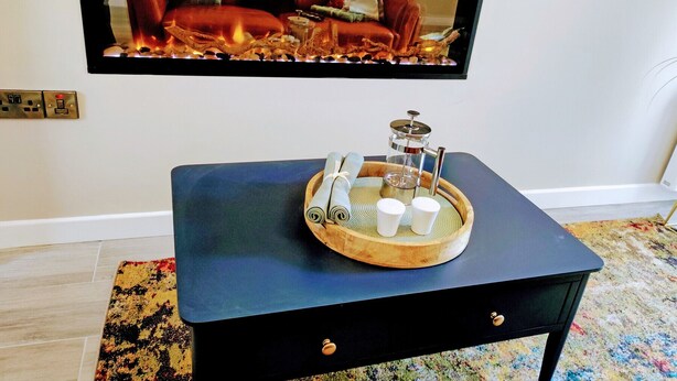 A black table with a wooden tray holding a coffee maker, salt and pepper shakers, and a rolled-up napkin. - Tralee Townhouse Holiday Home (Tralee)