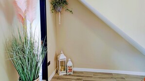 A hallway with a potted plant, a hanging plant, and a white lantern on the floor. - Tralee Townhouse Holiday Home (Tralee)