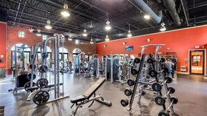 Uma academia com diversos equipamentos de musculação, bancos e halteres.
