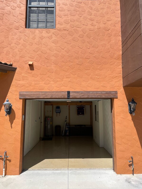 A garage with a concrete floor, a wooden door, and a small window with blinds.