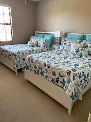 Een slaapkamer met twee bedden, elk voorzien van passend blauw-wit beddengoed met afbeeldingen van zeedieren.