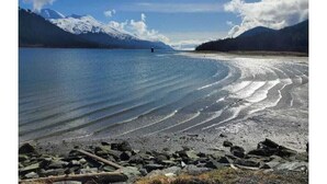 Un lac aux rives rocheuses, avec des montagnes en arrière-plan.