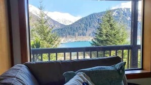 Une pièce avec vue sur un lac et des montagnes, grâce à une grande fenêtre.