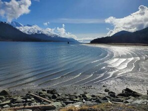 A lake with a rocky shoreline and mountains in the background.