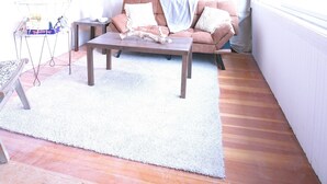 A cozy loft-style room with a wooden ceiling, a sofa set, a coffee table, and a large window with curtains. - Rustic cottage-style condo within walking distance to downtown Homewood (Homewood)