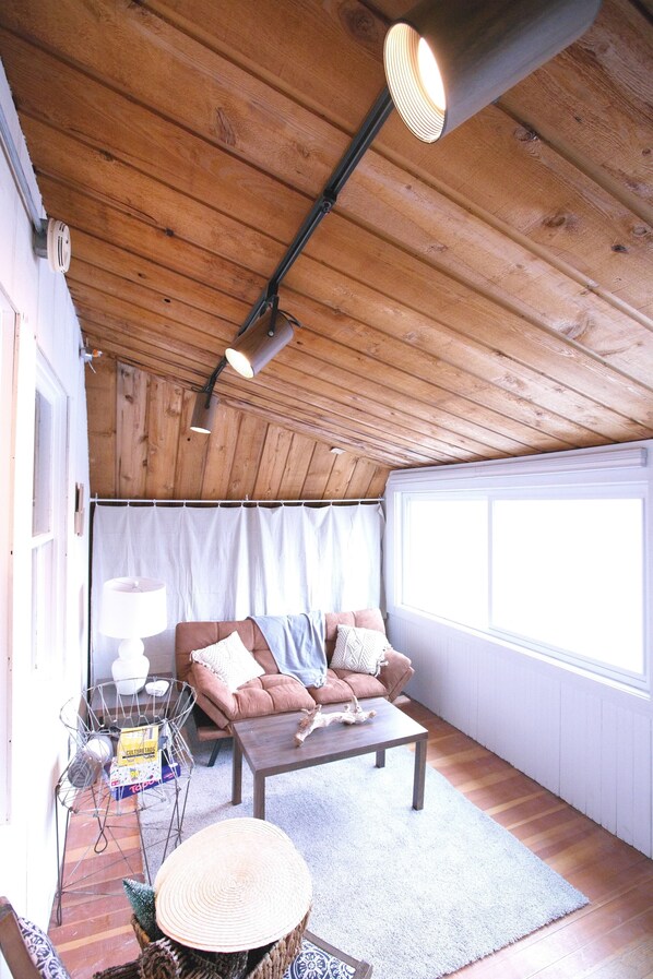 Una habitación acogedora con techo de madera, un sofá, una mesa de centro y un ventanal.