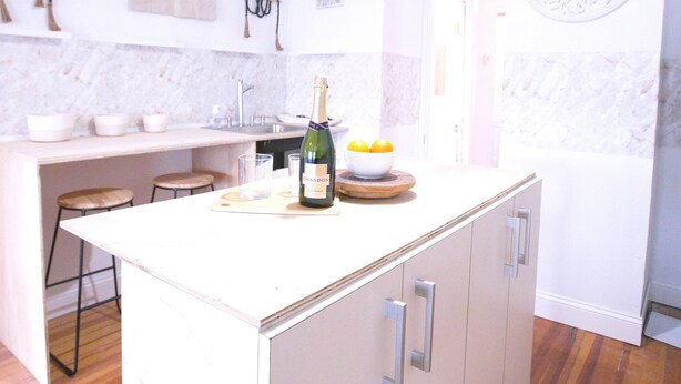 A modern kitchen with a central island, white cabinetry, and a hanging light fixture. - Rustic cottage-style condo within walking distance to downtown Homewood (Homewood)
