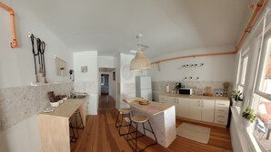 A modern kitchen with a central island, wooden stools, and a hanging light fixture. - Rustic cottage-style condo within walking distance to downtown Homewood (Homewood)