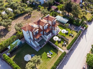 Ein mehrstöckiges Haus mit Terrasse, Sitzgelegenheiten im Freien und einem Garten.
