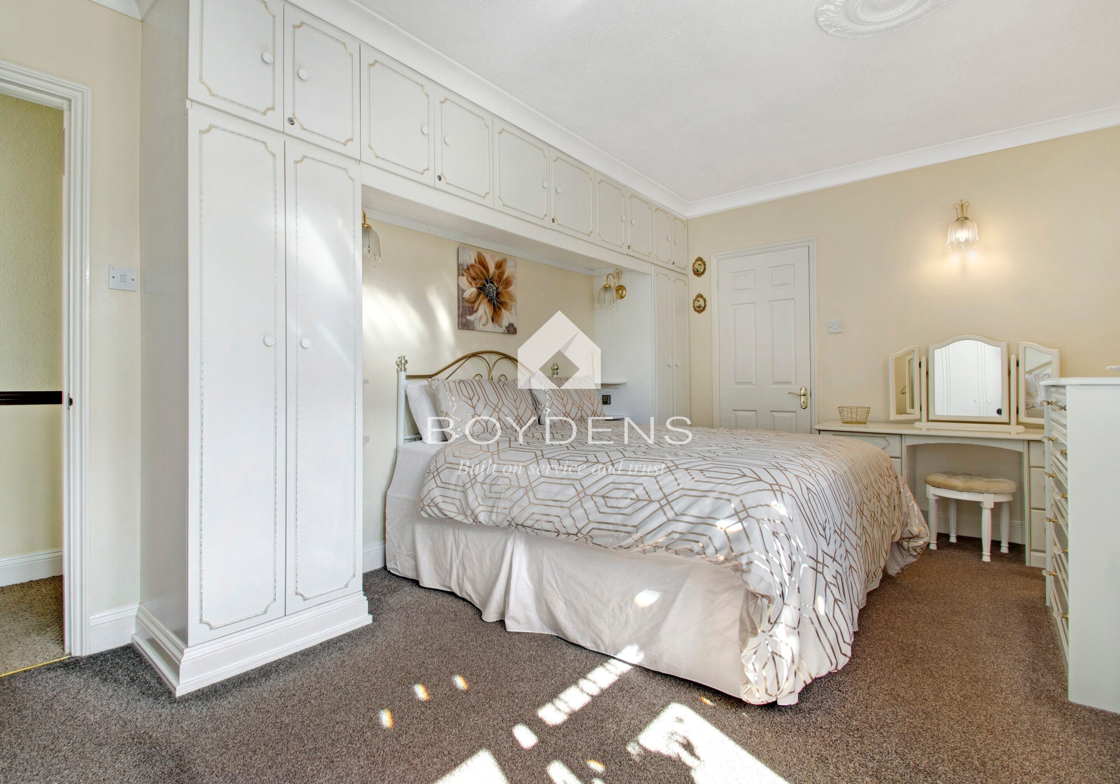 A bedroom with a bed, a desk, and a wardrobe.