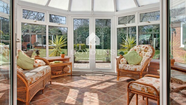 A conservatory with wicker furniture, large windows, and a tiled floor. - Wix, with its rolling countryside and reputation as a peaceful village, perfect for a rural stay (Manningtree)