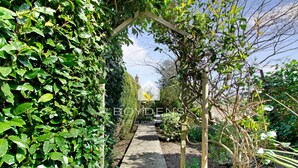 A garden pathway with a wooden archway, surrounded by dense foliage. - Wix, with its rolling countryside and reputation as a peaceful village, perfect for a rural stay (Manningtree)