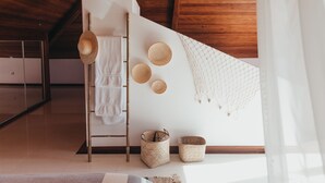 Ein modernes Interieur mit Holzboden, einer weißen Wand mit gewebten Körben, einer Leiter und einer Hängematte.