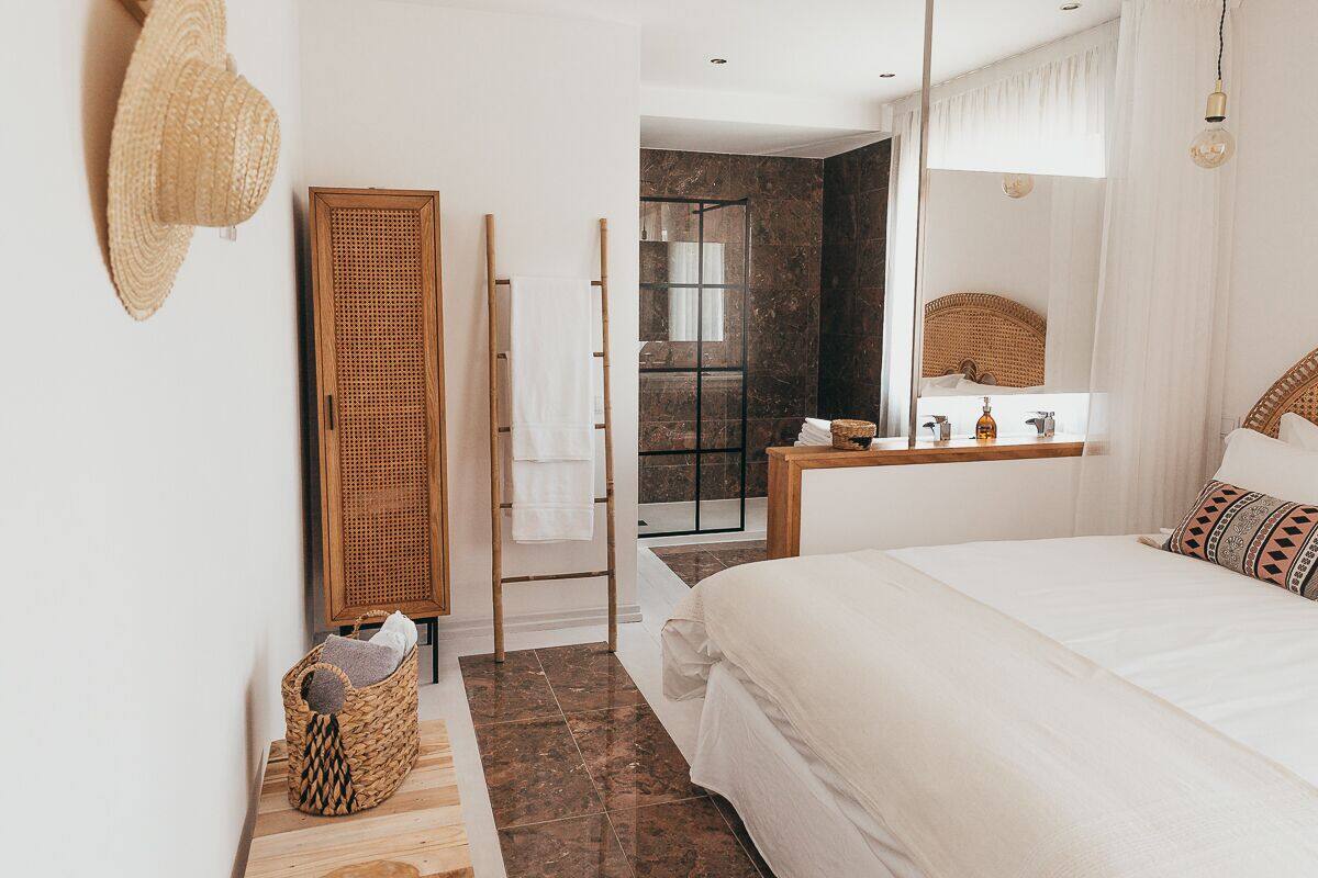 Un dormitorio con una cama grande, una mesita de noche de madera, un espejo y una zona de ducha.