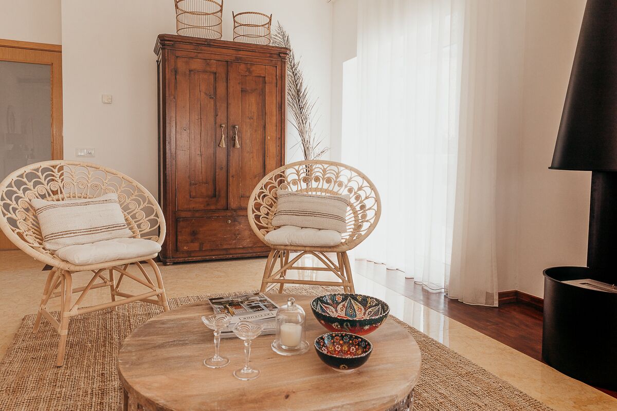 A cozy living room with wicker chairs, a wooden coffee table, and a cabinet.