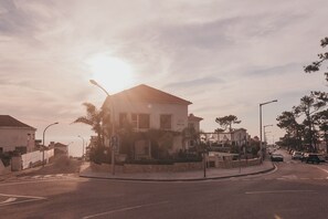 A building with a tiled roof, a sign reading "JOY", and a street with cars and trees. - Joy Beach House (Marinha Grande)